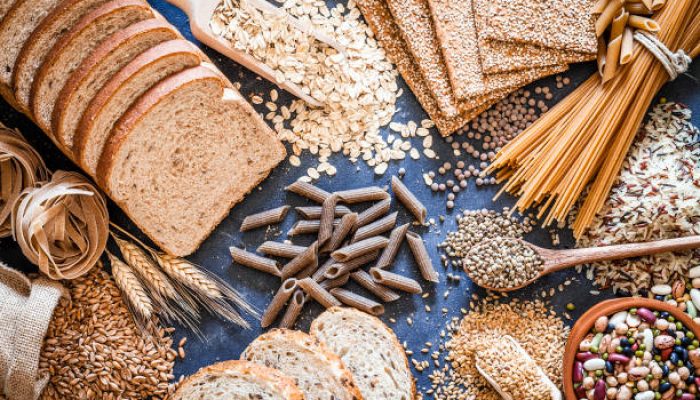 Top view of wholegrain and cereal composition shot on rustic wooden table. This type of food is rich of fiber and is ideal for dieting. The composition includes wholegrain sliced bread, wholegrain pasta, oat flakes, flax seed, brown rice, mixed beans, wholegrain crackers and spelt. Predominant color is brown. DSRL studio photo taken with Canon EOS 5D Mk II and Canon EF 100mm f/2.8L Macro IS USM